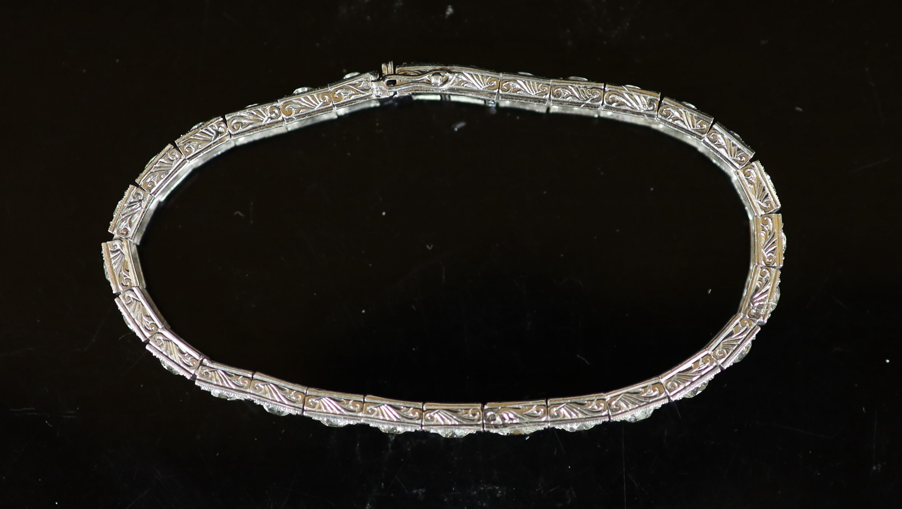 A mid 20th century engraved platinum and graduated old round cut diamond set line bracelet